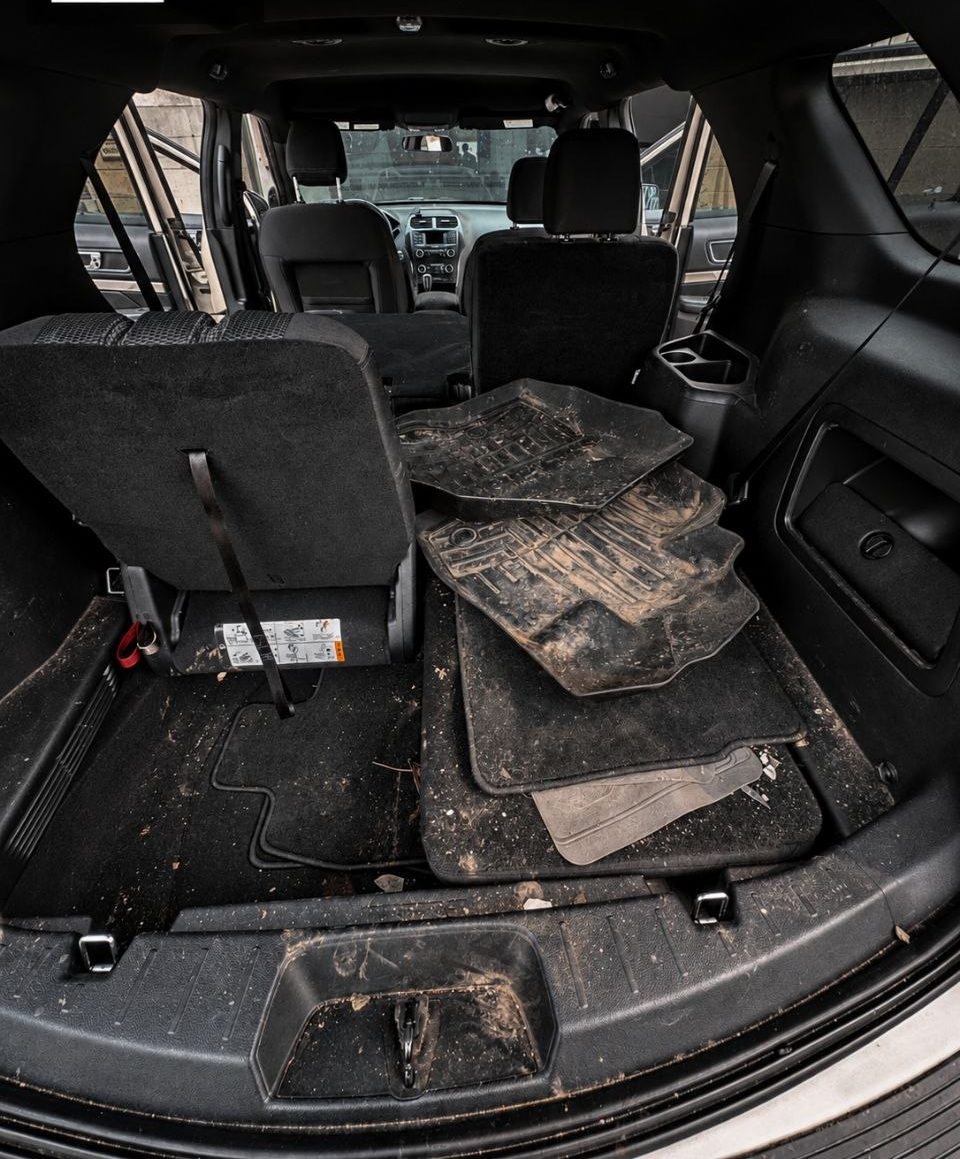Dirty SUV third-row cargo and floor mats before detailing